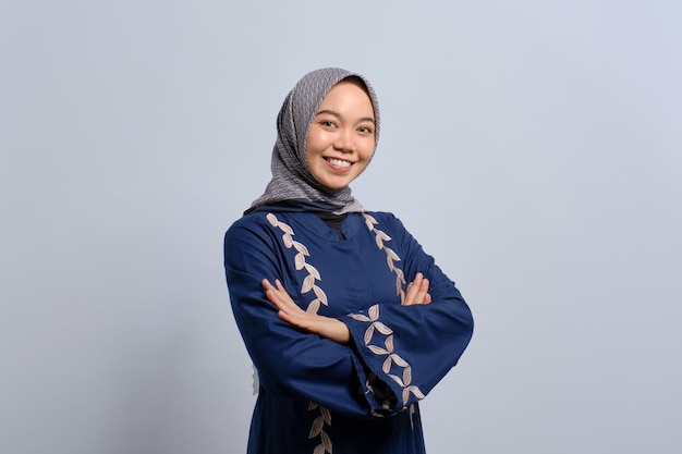 Smiling young Asian Muslim woman standing with crossed arms and looking confident isolated over white background