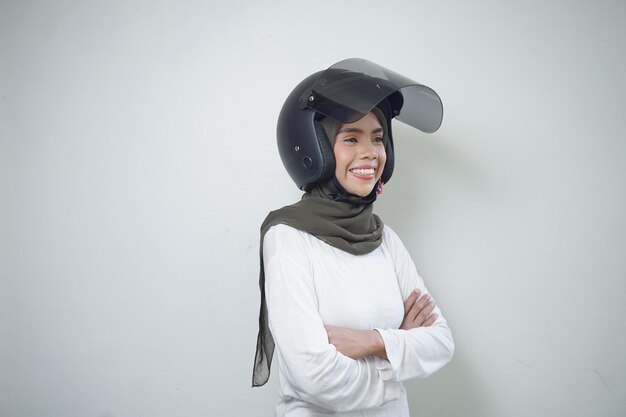 Smiling young Asian muslim woman using motorcycle helmet isolated on white background