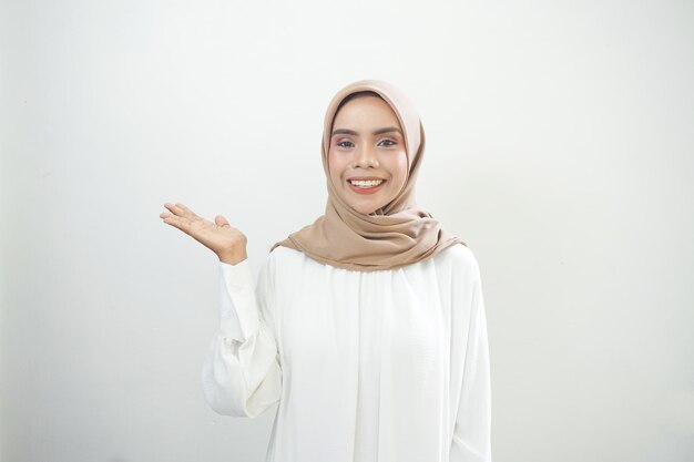 手のひらにコピー スペースを示すカジュアルな服を着て笑顔の若いアジアのイスラム教徒の女性