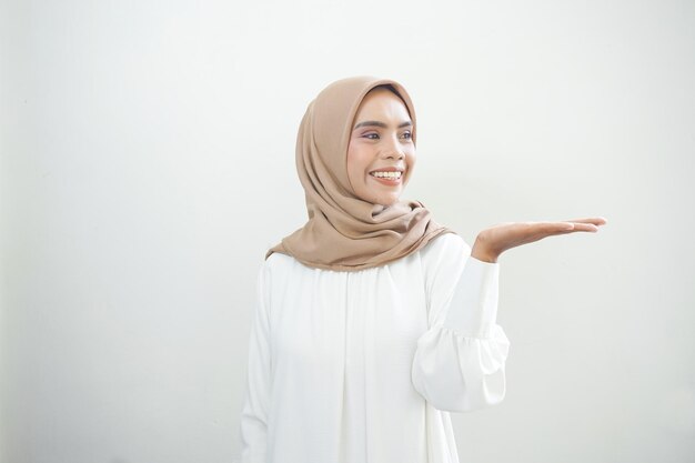 Smiling young Asian muslim woman in wearing casual clothes showing copy space on palm