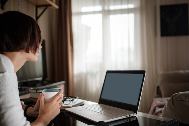 Smiling young asian woman video calling on laptop