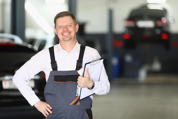 Smiling young auto mechanic accepting an auto in repair
