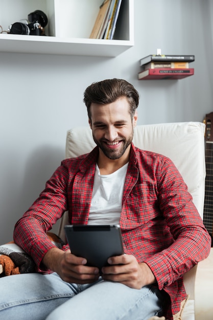 Smiling young bearded man using tablet computer.