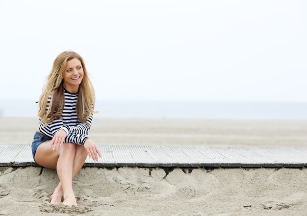 Smiling young blond woman sitting at the beach