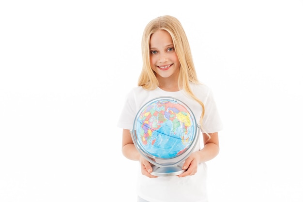 Улыбающаяся молодая блондинка в повседневной одежде держит глобус на белом