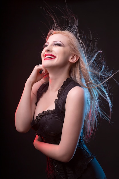 Smiling young blonde woman in corset with hair in motion