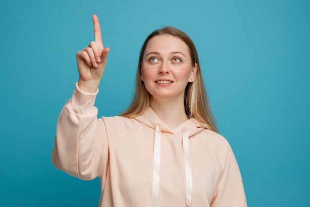 Smiling young blonde woman looking and pointing up 