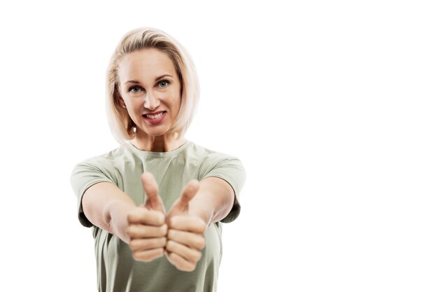 Smiling young blonde woman showing thumbs up. Isolated on a white background. Space for text.