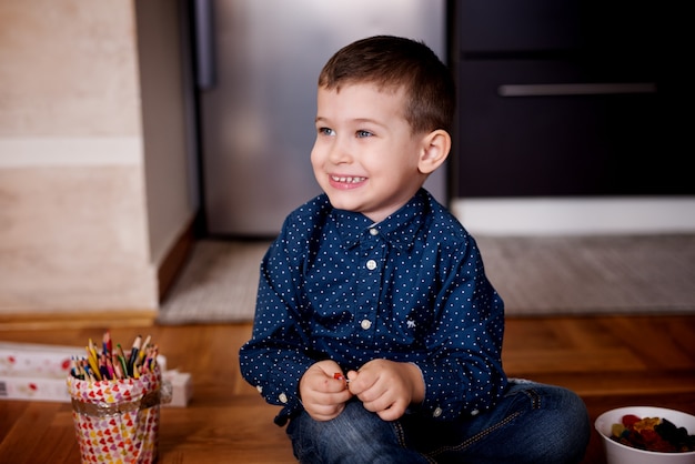 Smiling young boy, playing with his toys on the floor. Careless childhood.