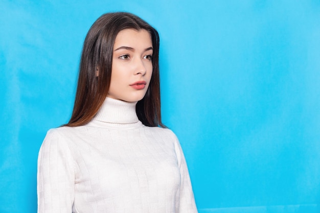 Smiling young brunette woman girl in casual white clothes posing isolated on pastel blue background studio portrait People emotions lifestyle concept Mock up copy space Looking camera