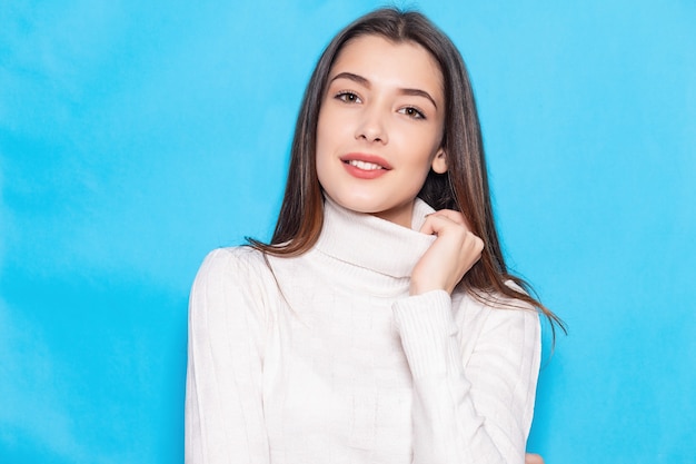 Smiling young brunette woman girl in casual white clothes, posing isolated on pastel blue background studio portrait. People emotions lifestyle concept. Mock up copy space. Looking camera