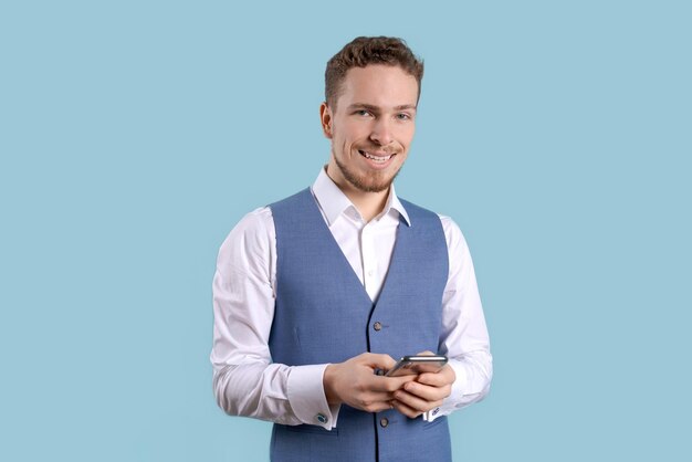 Smiling young business man using smartphone to contact family and friends or