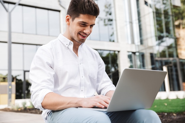 Smiling young business man working on laptop computer