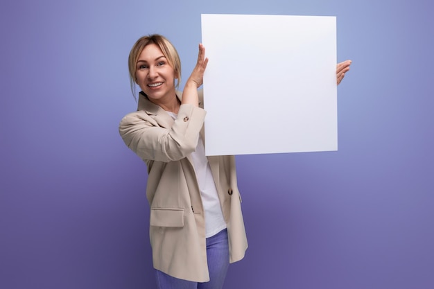 Smiling young business woman demonstrating a paper sheet with a layout for information on a studio