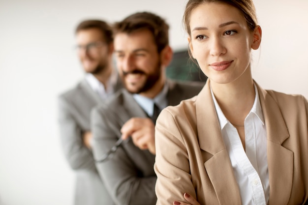 Smiling young business woman standing with group of corporate colleagues in a row together at the office