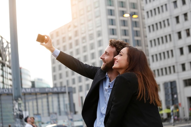 Smiling young businessman and businesswoman taking selfie outdoors