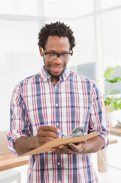 Smiling young businessman looking at the clipboard