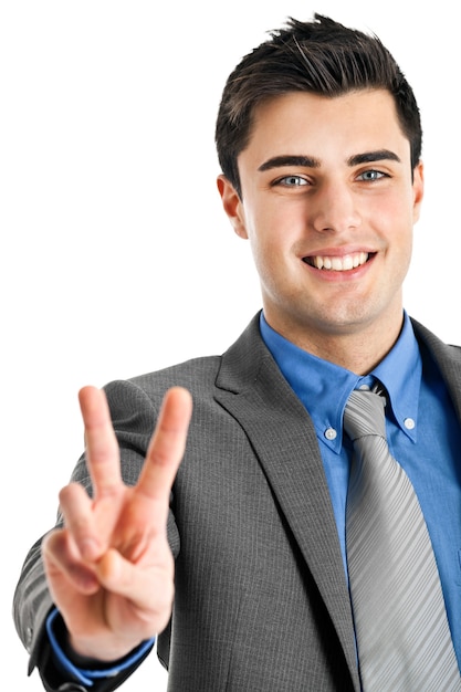 Smiling young businessman showing victory gesture