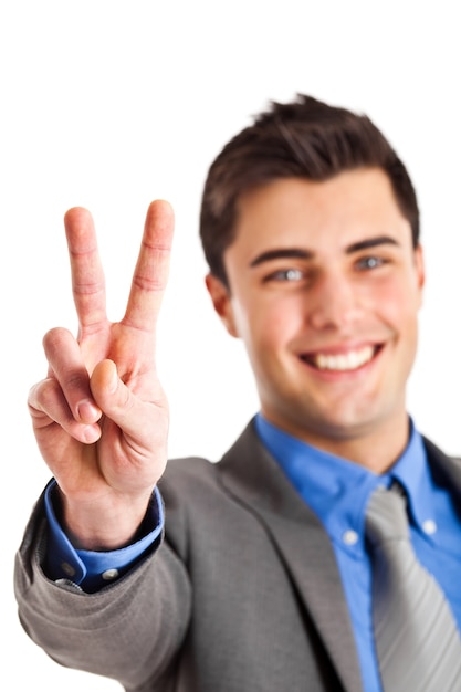 Smiling young businessman showing victory gesture