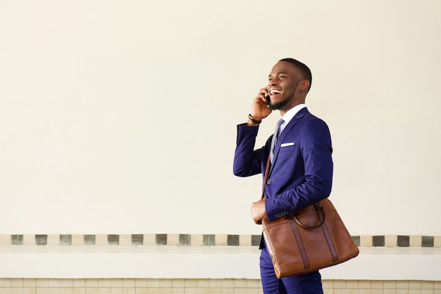 Smiling young businessman walking and talking on mobile phone 