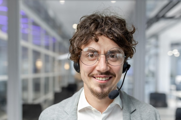 Smiling young businessman with curly hair wearing a headset in a modern office energetic male