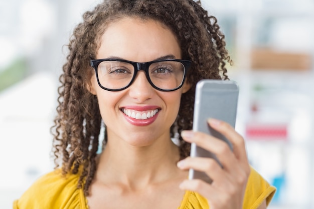 Smiling young businesswoman holding a smartphone