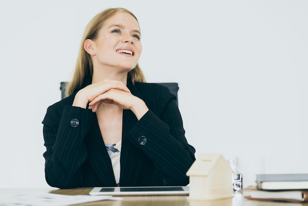 Photo smiling young businesswoman looking away at desk in office