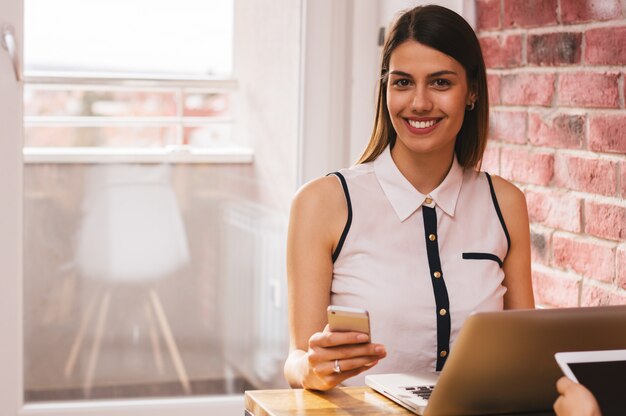 Smiling young businesswoman sending a text message in the home office