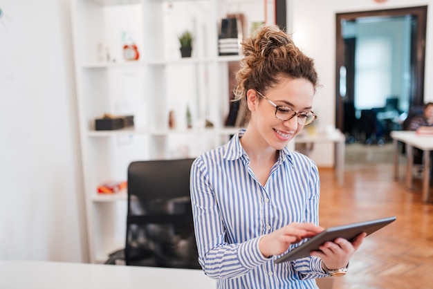 Smiling young businesswoman using digital tablet.