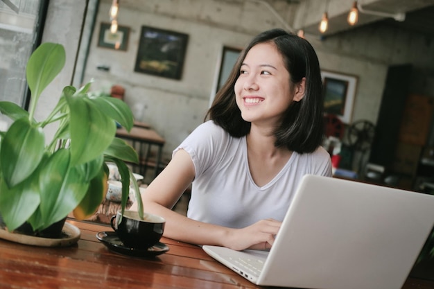 Photo smiling young businesswoman using laptop on table at cafe