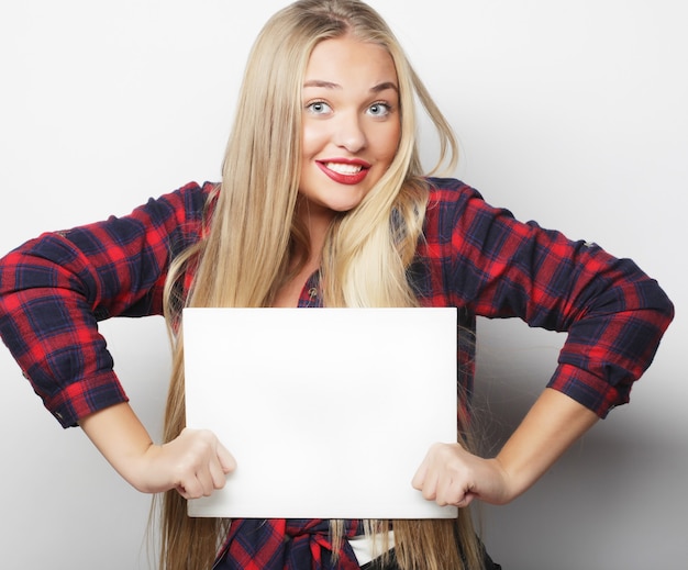 Smiling young casual style woman showing blank signboard, over white background isolated