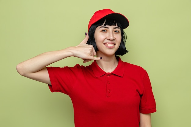 Smiling young caucasian delivery girl gesturing call me sign