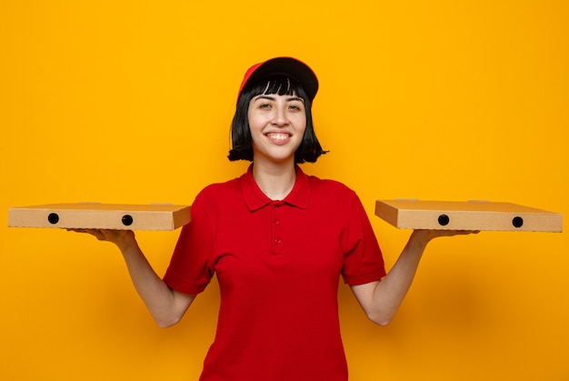 Smiling young caucasian delivery girl holding pizza boxes