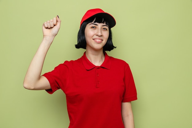 Smiling young caucasian delivery girl raising fist up