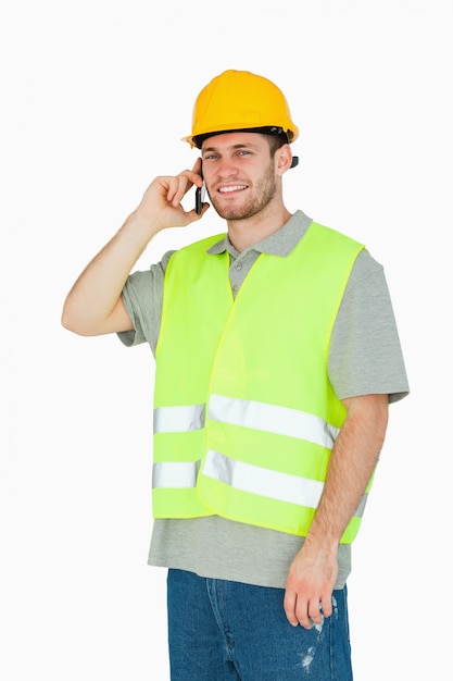 若い建設労働者が携帯電話で笑顔