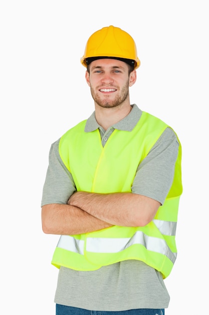 折り畳まれた腕を持つ若い建設労働者を笑顔