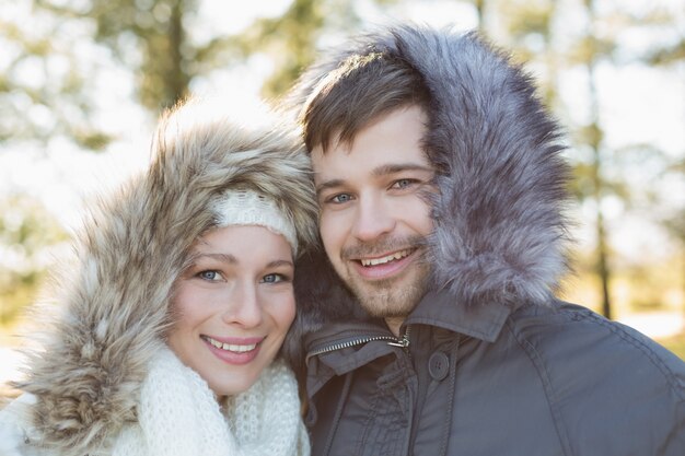 Smiling young couple in fur hood jackets in the woods