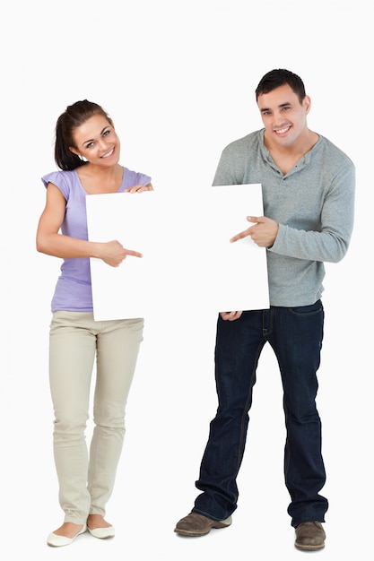 Smiling young couple holding sign together