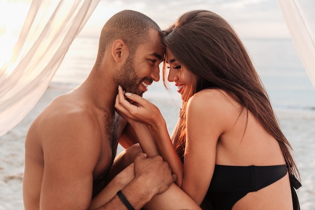 Smiling young couple hugging in bed on the beach