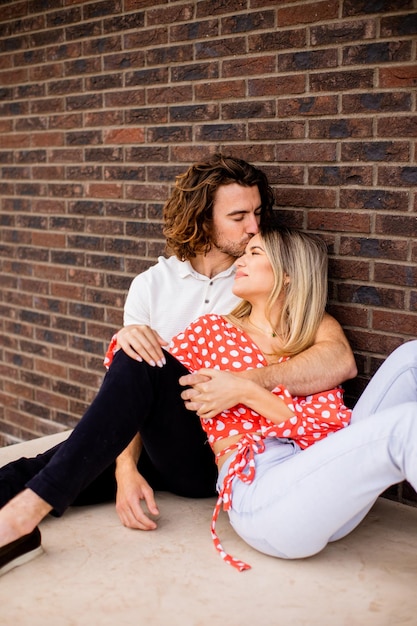 Smiling young couple in love in front of house brick wall