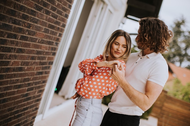 Smiling young couple in love standing in front of house brick wall