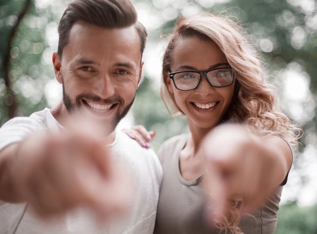 Smiling young couple pointing at you