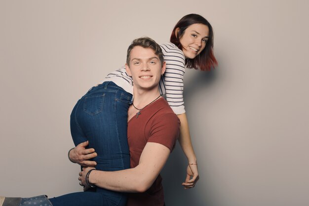 Photo smiling young couple posing over creme wall