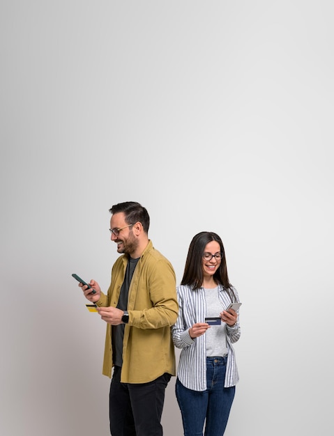 Smiling young couple shopping online with credit card and smart phones