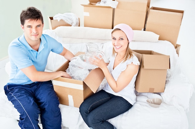 Smiling young couple unpacking boxes with glasses