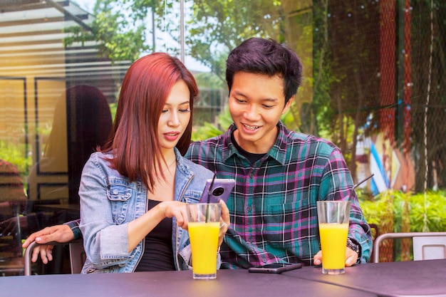 Smiling young couple using a smartphone in cafe