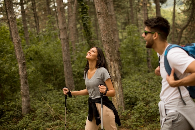 Smiling young couple walking with backpacks in the forest