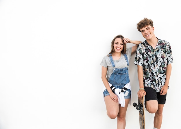 Smiling young couple with skateboard on white background