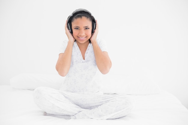 Smiling young dark haired model listening to music with headphones