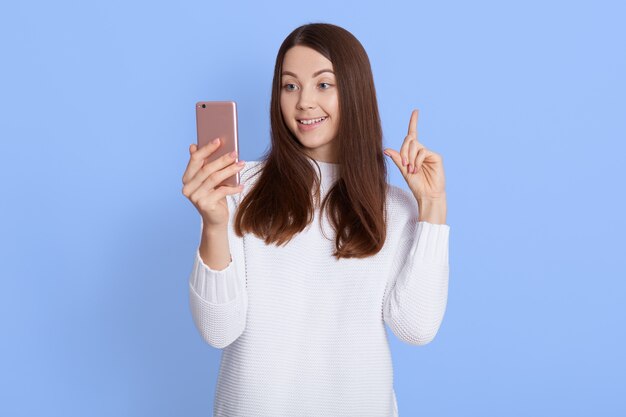 Smiling young dark haired woman girl in white sweater posing